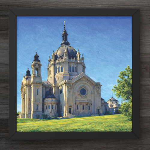 Framed artwork of a large cathedral with a blue sky and green grass.