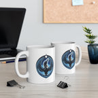 Two white mugs with blue and black designs on a desk with a laptop and plant in the background.