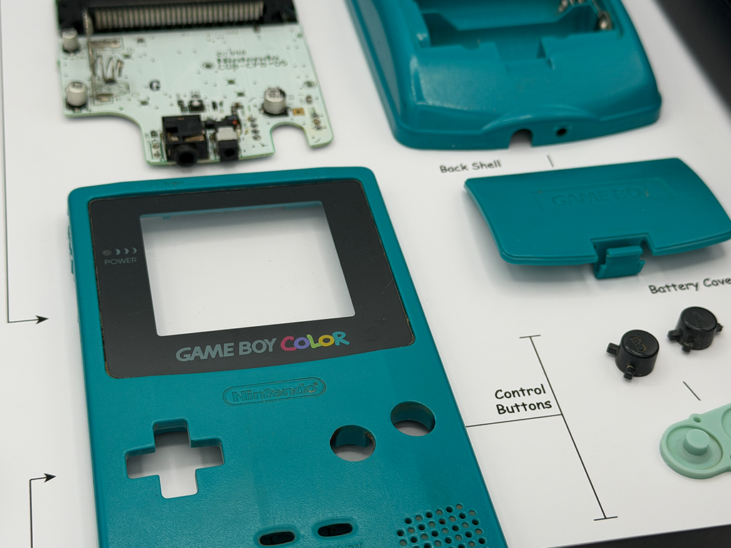 Teal Game Boy Color disassembled on a white surface with diagram labels.