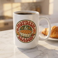 A white ceramic coffee mug with a 'Hotdish Season' graphic, filled with black coffee and sitting on a marble countertop next to a croissant.