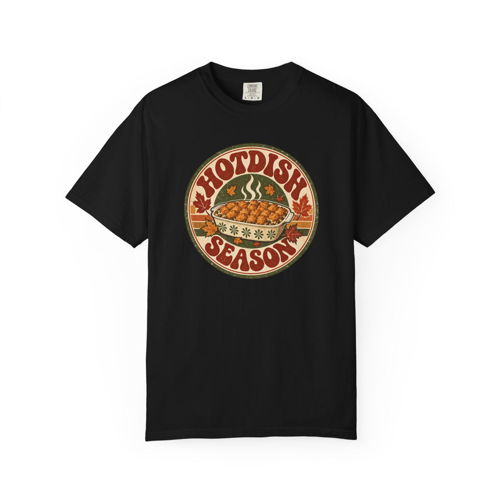A black t-shirt with a circular retro-style graphic that reads 'HOTDISH SEASON' around an illustration of a hot casserole dish, photographed on a clean white background.