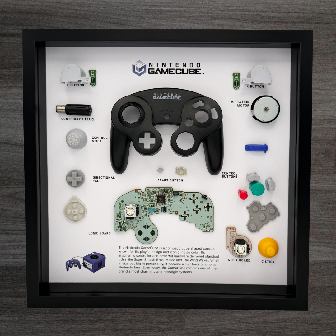 Framed display of a GameCube controller with labeled parts on a wooden surface