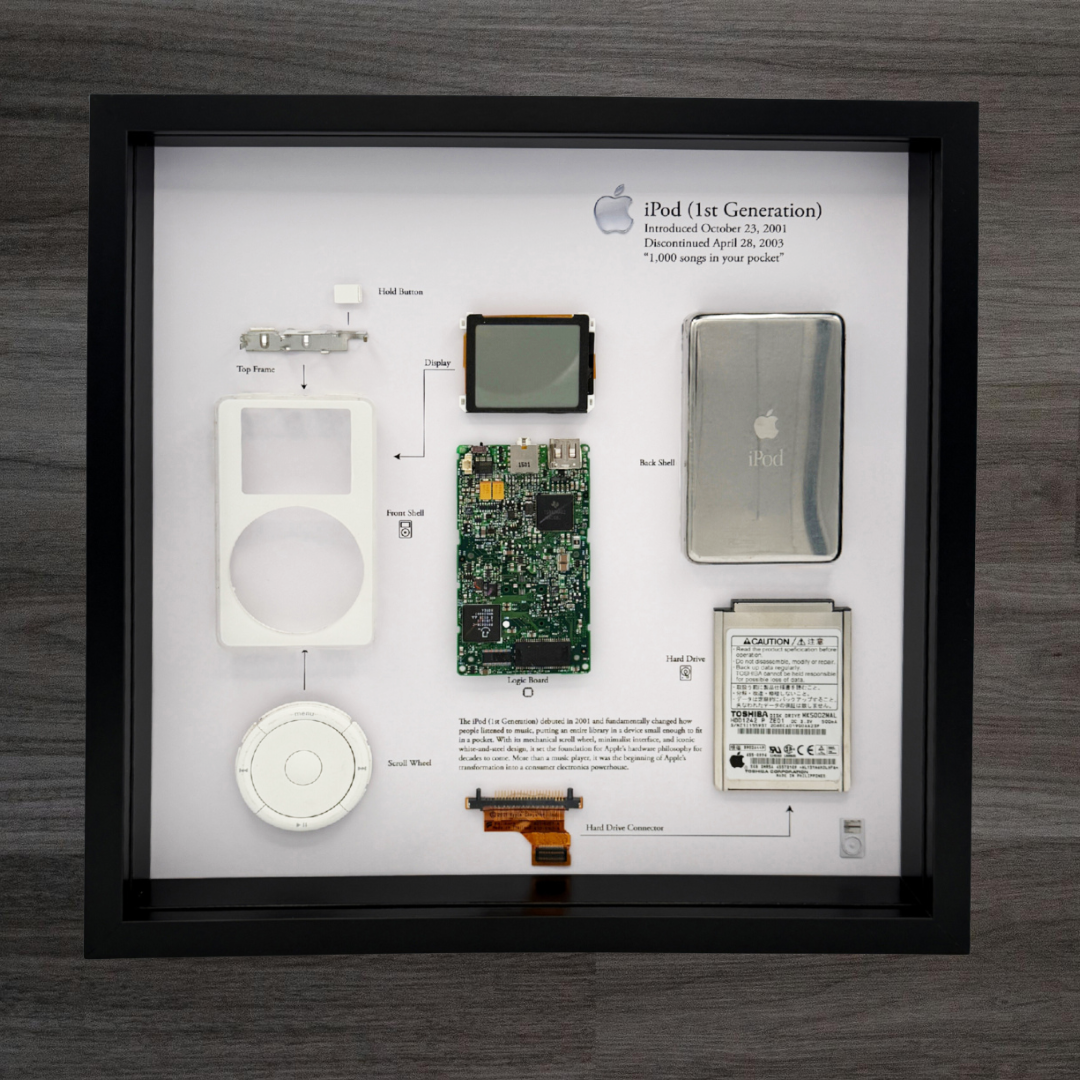 Framed display of Apple iPod 1st generation components on a wooden surface