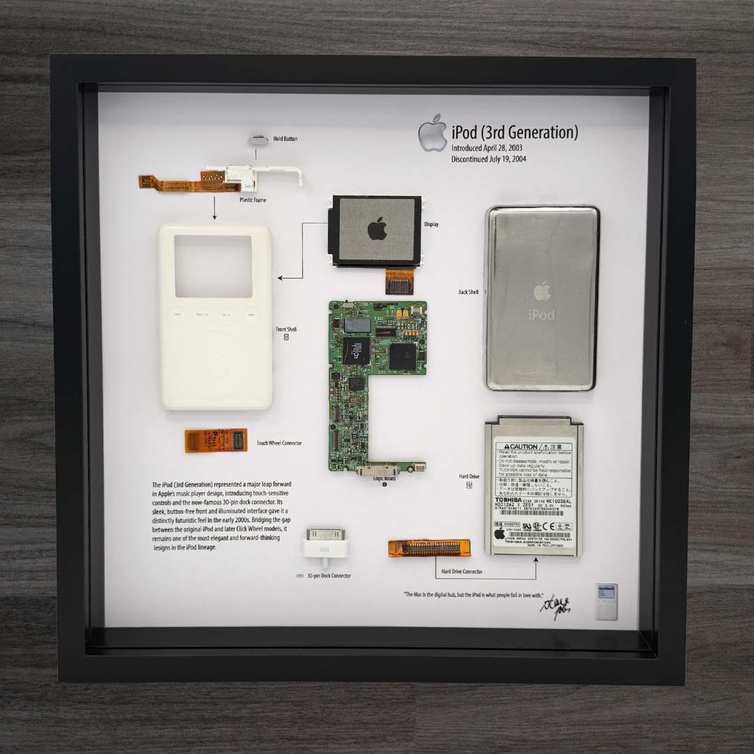Framed display of Apple iPod 3rd generation components on a wooden surface