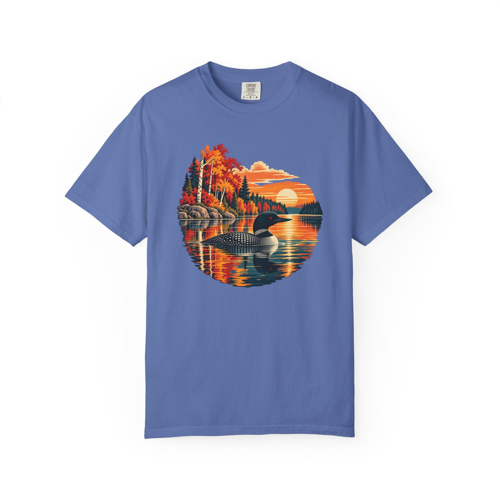 A blue short-sleeve crewneck t-shirt featuring a circular graphic print of a loon in a lake surrounded by colorful autumn trees and a sunset.
