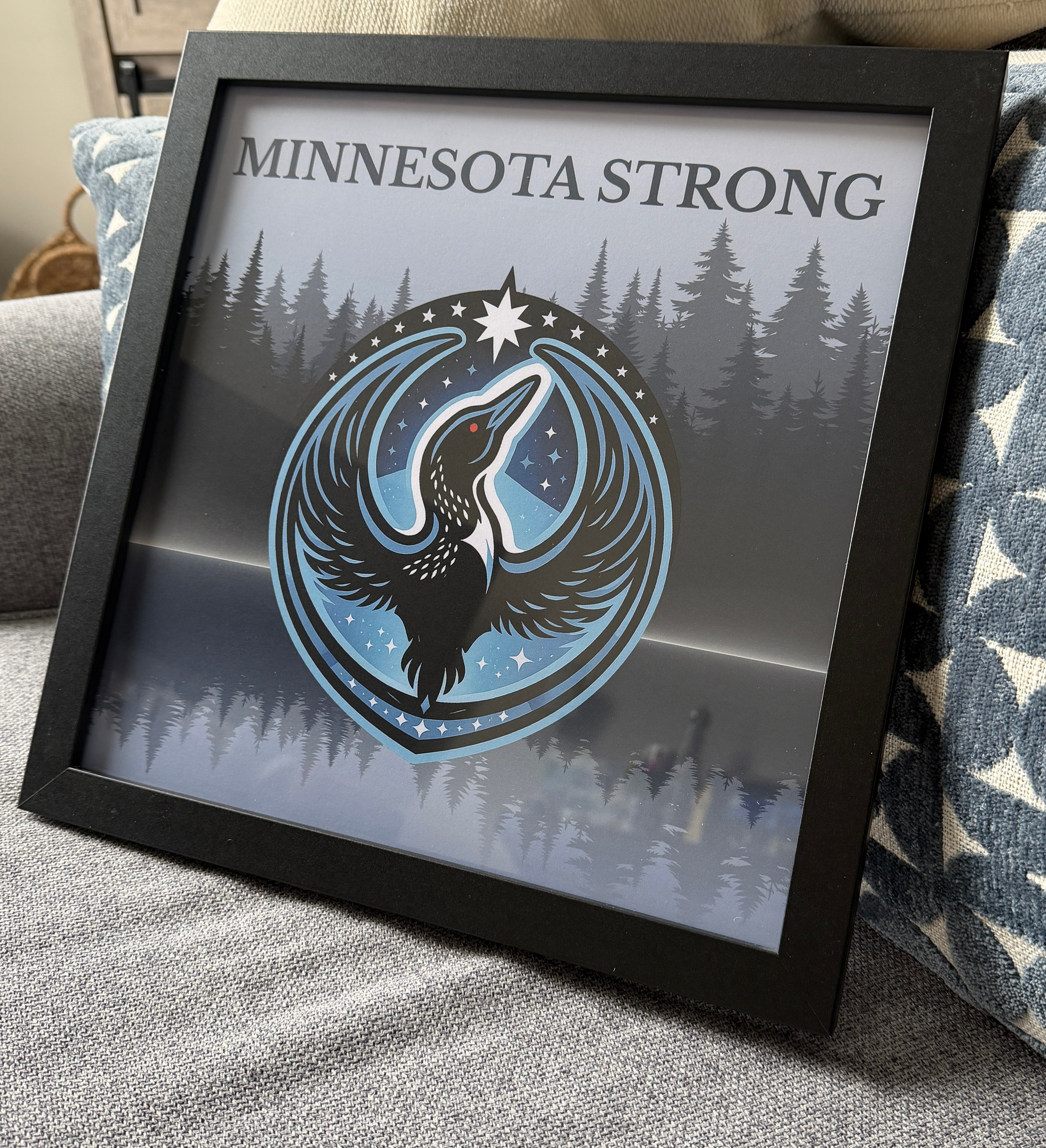 Framed artwork with 'Minnesota Strong' text and a loon design on a forest background.