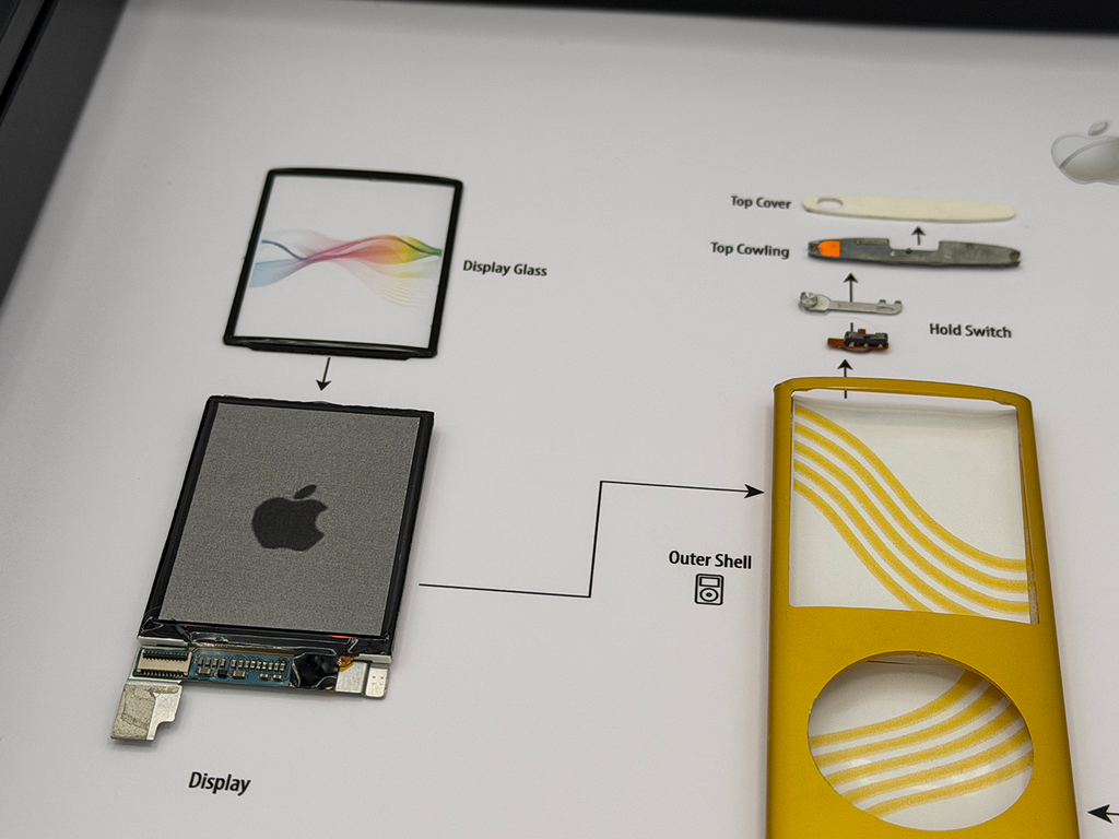 Disassembled Apple product with labeled parts on a white background