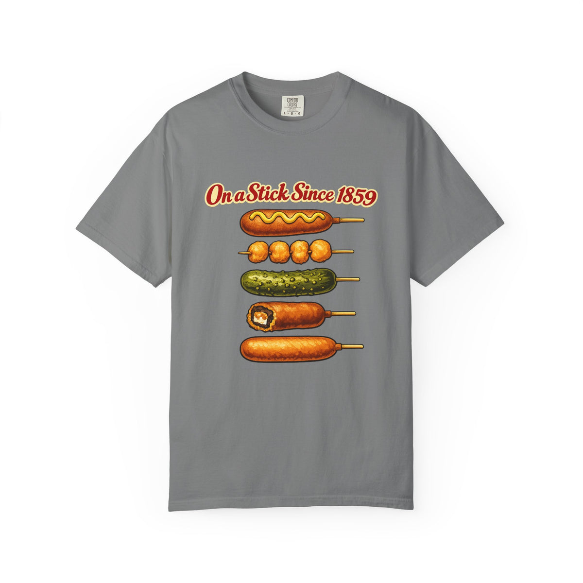 A gray short-sleeve crewneck t-shirt featuring a graphic print of various corn dogs and hot dogs stacked vertically with the text 'On a Stick Since 1859' in red above them, displayed on a clean white background.