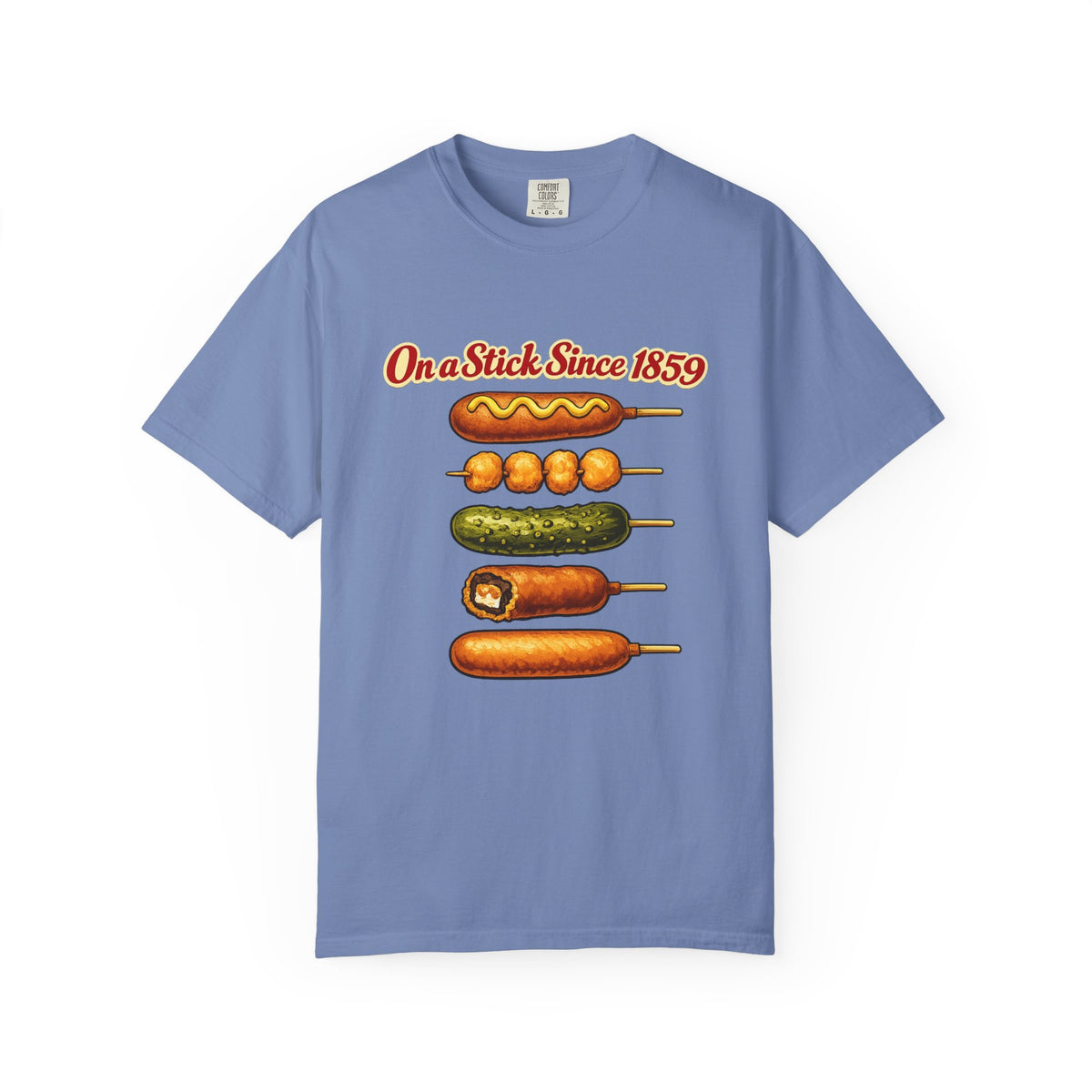 A light blue crewneck t-shirt featuring a graphic print of various corn dogs on sticks with the text 'On a Stick Since 1859' in red and yellow, displayed against a plain white background.
