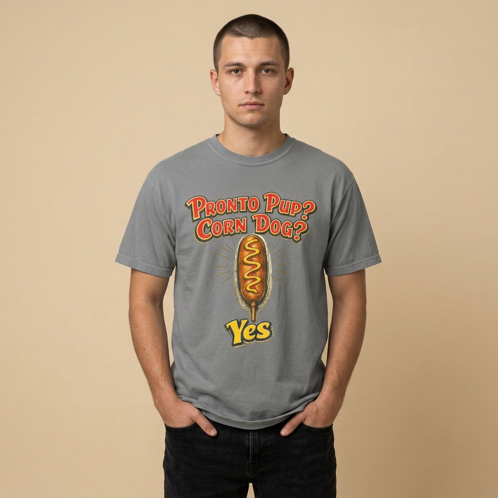 A man wearing a heather gray graphic t-shirt with a 'Pronto Pup? Corn Dog? Yes' design, standing against a solid beige background.