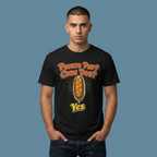 A man wearing a black graphic t-shirt with a corn dog design and the text 'Pronto Pup? Corn Dog? Yes' against a solid blue-gray background.