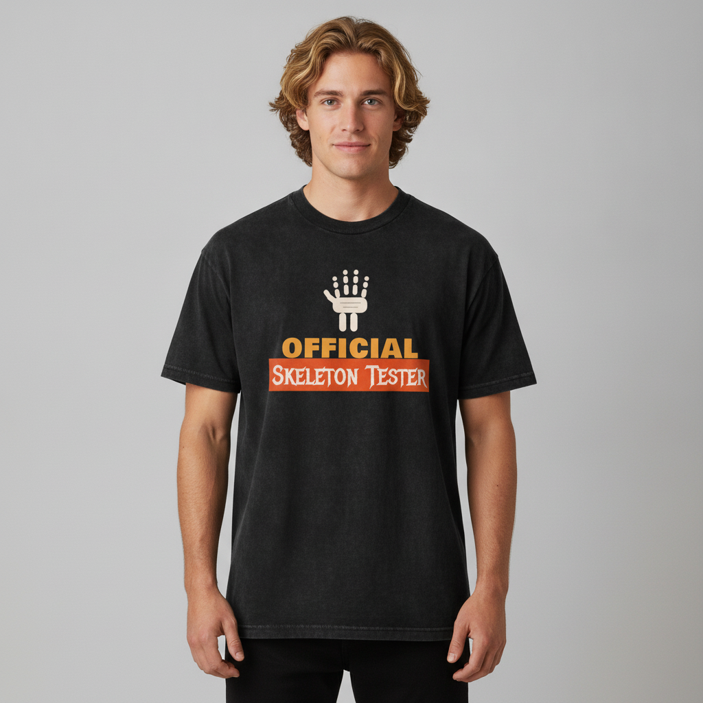 A man wearing a black graphic t-shirt with a white skeleton hand and orange text reading 'OFFICIAL SKELETON TESTER' on a gray studio background.