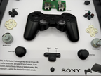 Black PS3 gaming controller on a white background with text and branding