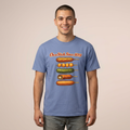A man wearing a heathered blue t-shirt with a graphic of various hot dogs on sticks and the text 'On a Stick Since 1859' printed on the chest, set against a solid beige background.