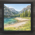 Framed artwork of a mountain lake scene with a person standing on the shore.