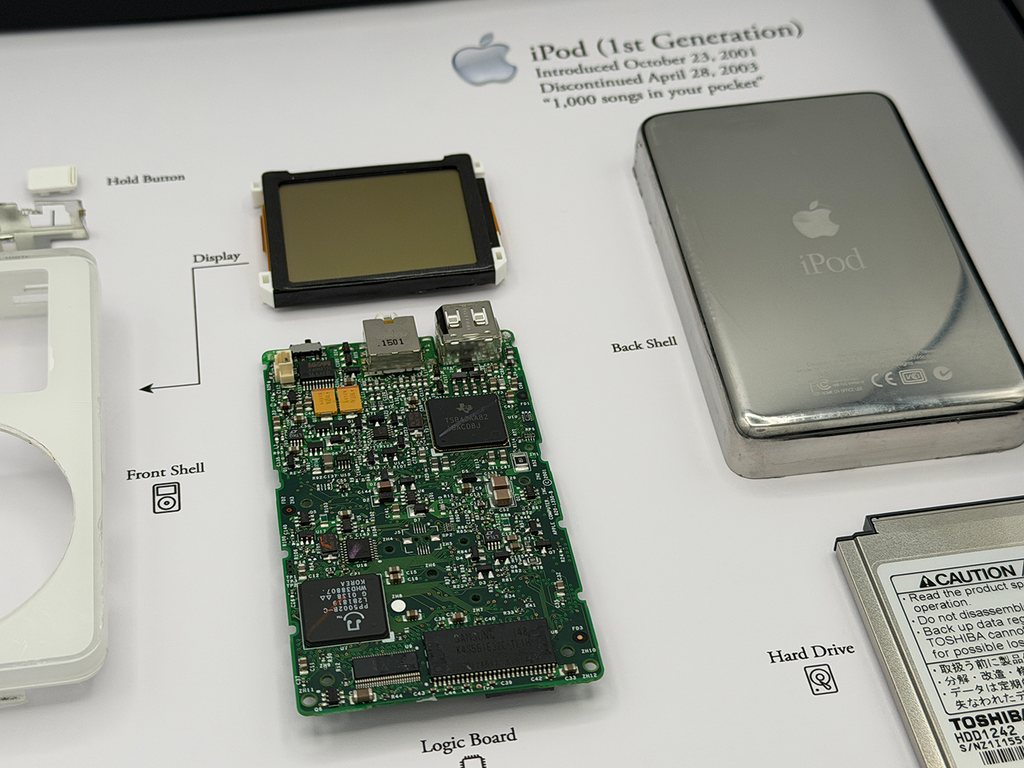 Disassembled iPod 1st Gen with its components on a white background